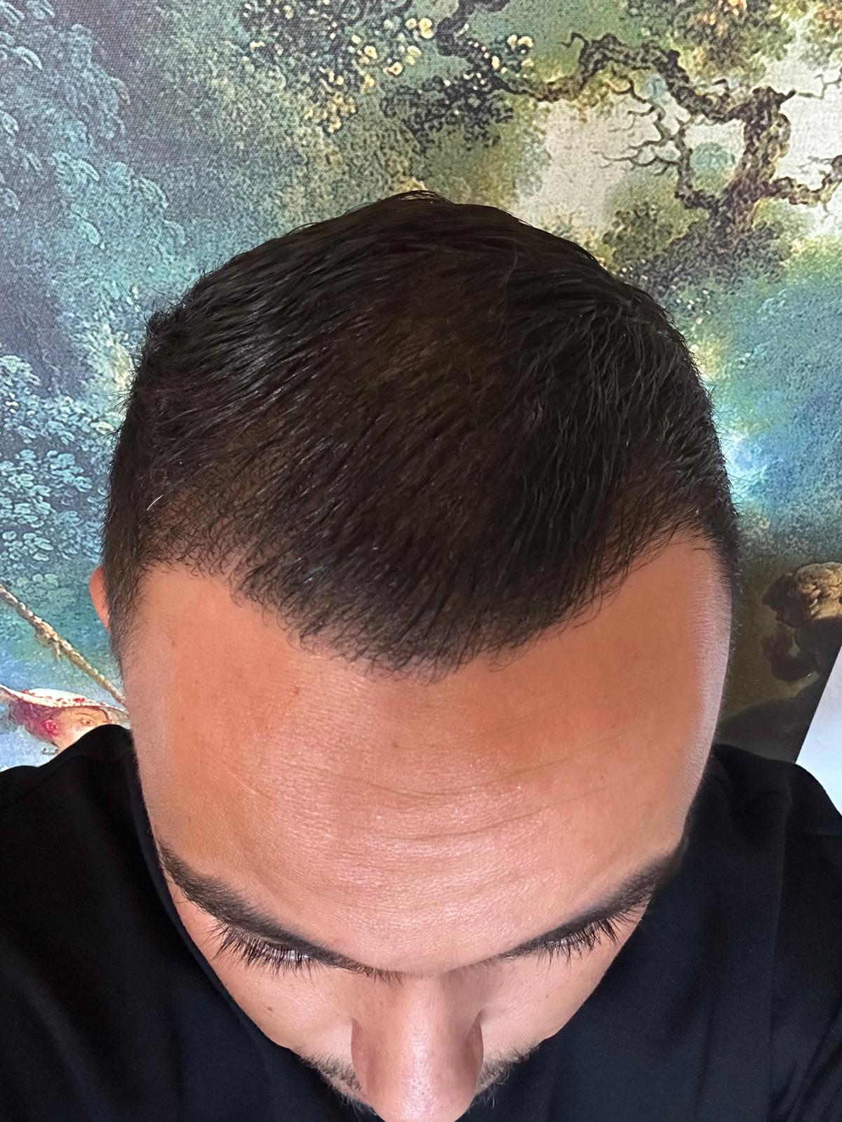 Ein Mann mit kurzen dunklen Haaren schaut nach unten vor einem farbigen Hintergrund